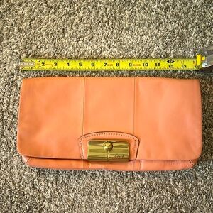 Salmon colored Coach clutch with gold hardware